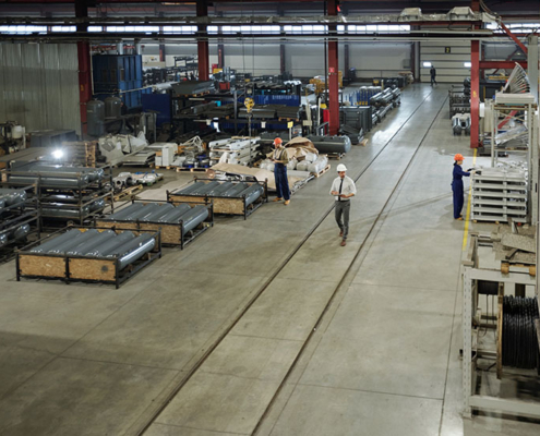 Großräumige Industriehalle mit Fertigungsanlagen und Mitarbeitern. Symbolisiert die Produktionskraft und Vielfalt mittelständischer Unternehmen.